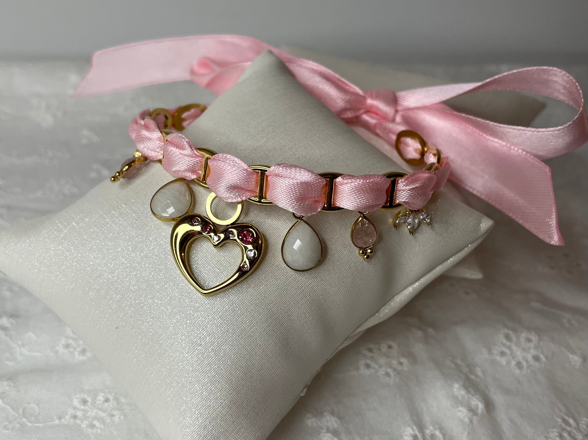 Bracelet ajustable en acier inoxydable avec son ruban rose pale et ses breloques