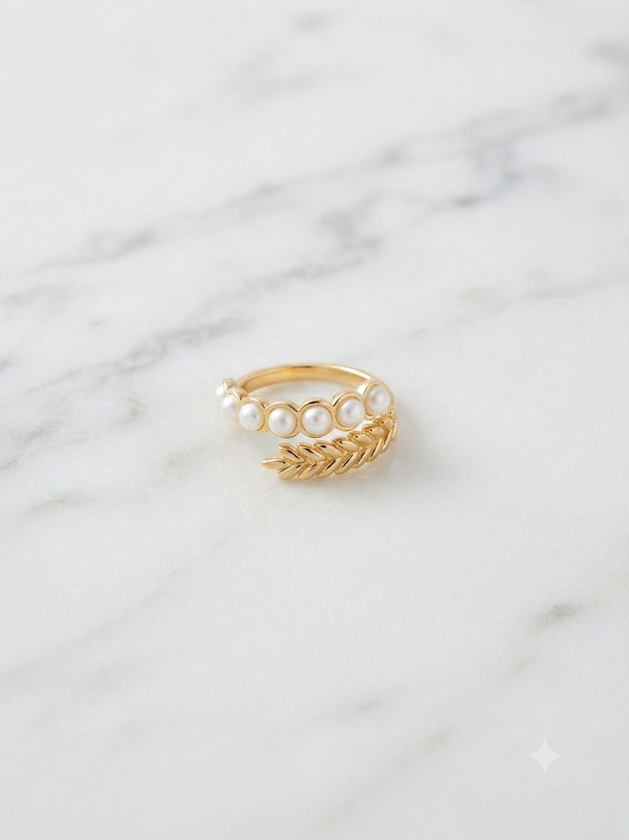 Bague Césara dorée ajustable ornée de perles, posée sur fond marbre blanc
