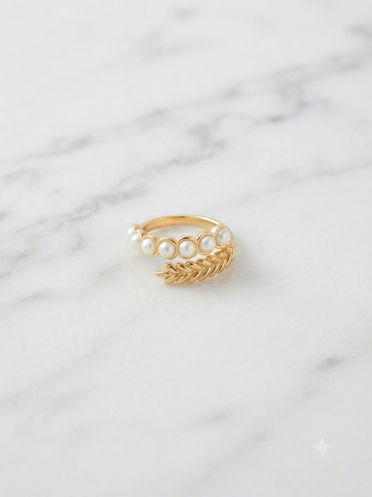 Bague Césara dorée ajustable ornée de perles, posée sur fond marbre blanc