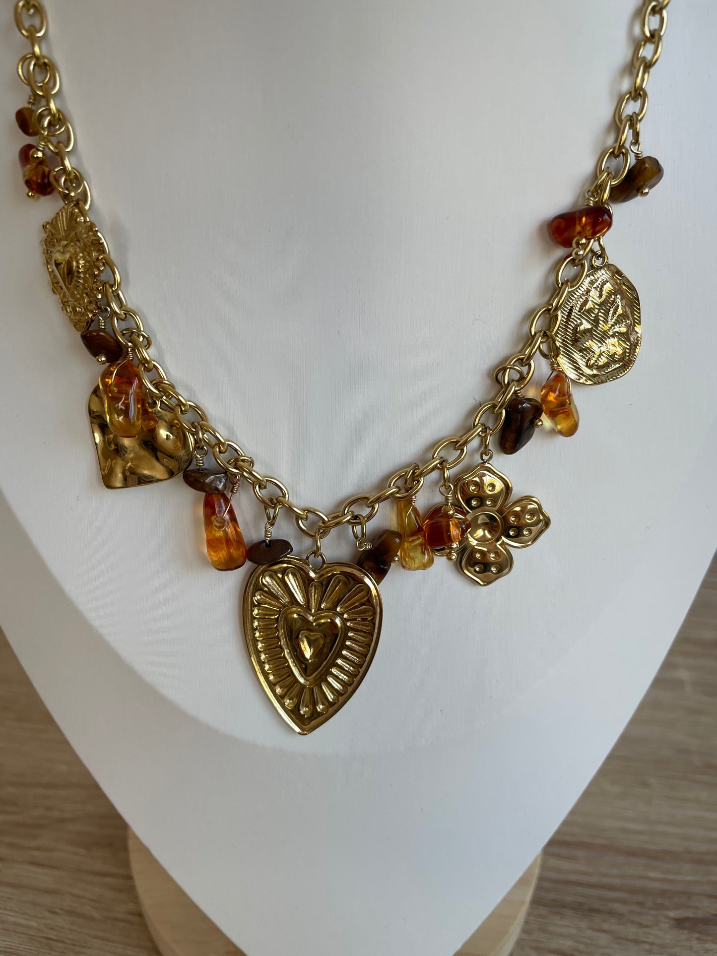 Gros plan des breloques et perles ambrées du collier Lovia en acier inoxydable
