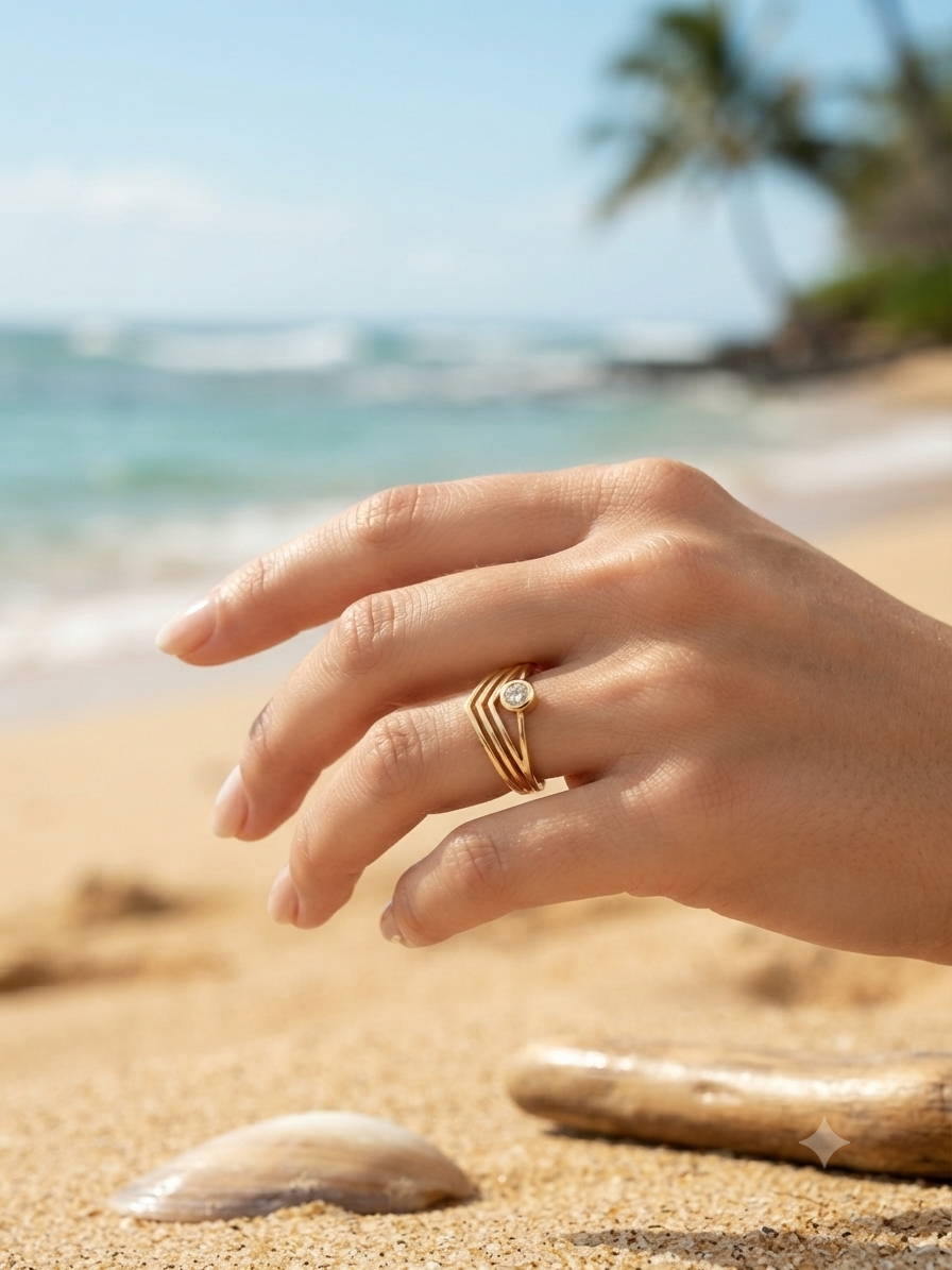Bague Athéna dorée anneaux chevrons et zircon portée à la main, ambiance plage