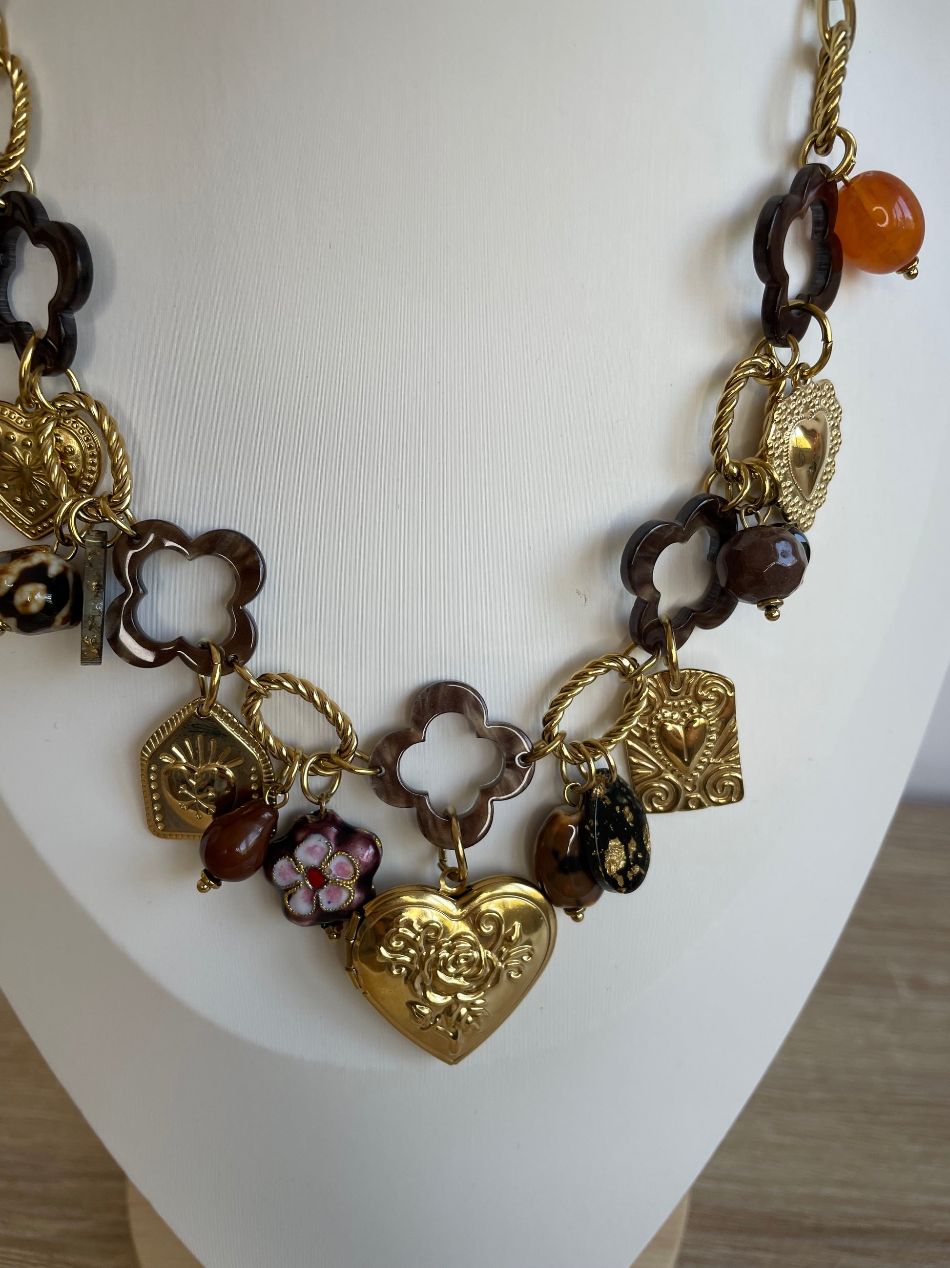 Gros plan des breloques cœurs et perles vintage du collier Amor en acier inoxydable