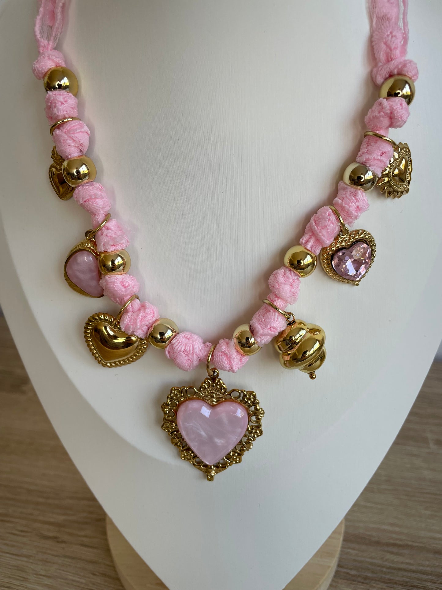 Gros plan du collier Lovéa rose avec breloques cœur dorées et pierre rose