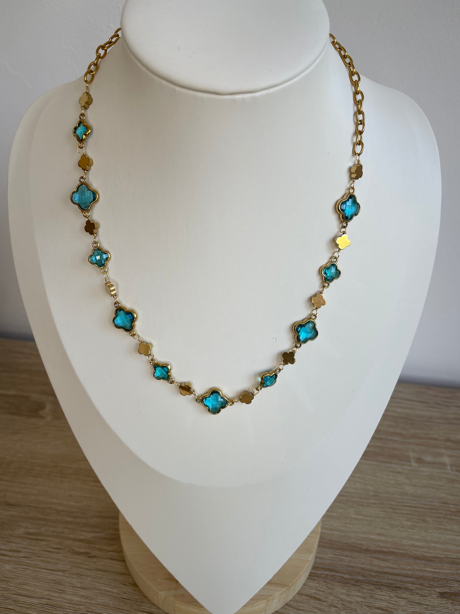 Collier Stacy bleu porté sur buste, chaîne trèfle acier inoxydable doré
