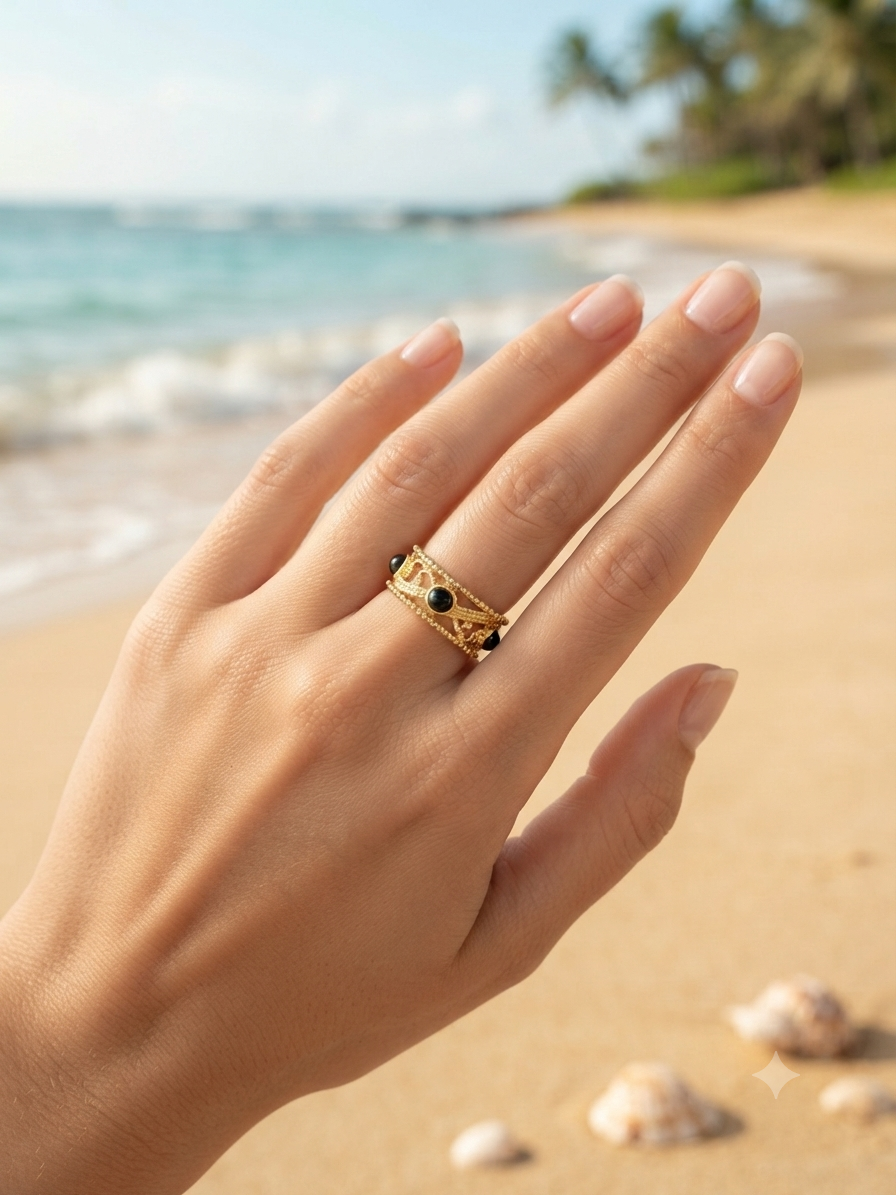 Bague Nymphe dorée portée à la main sur fond de plage
