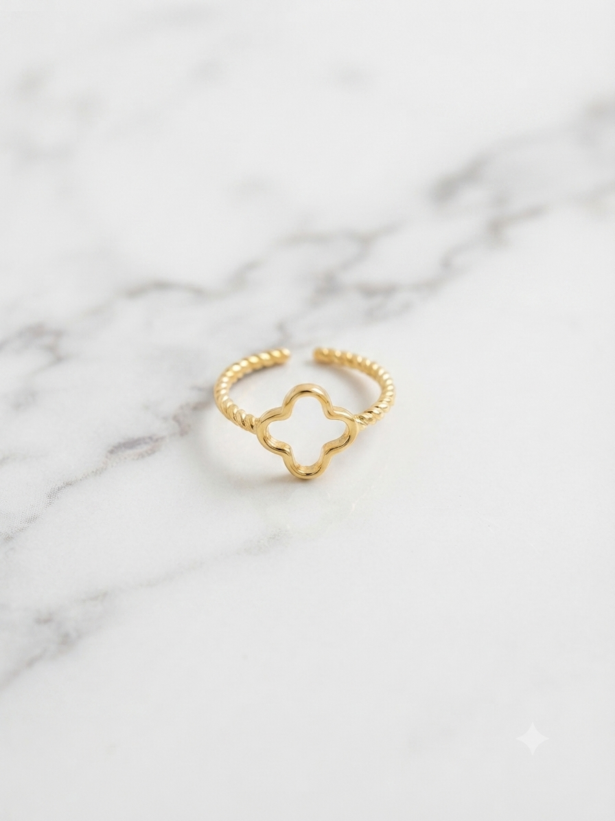 Bague Trèfle dorée ajourée posée sur marbre, gros plan sur le motif