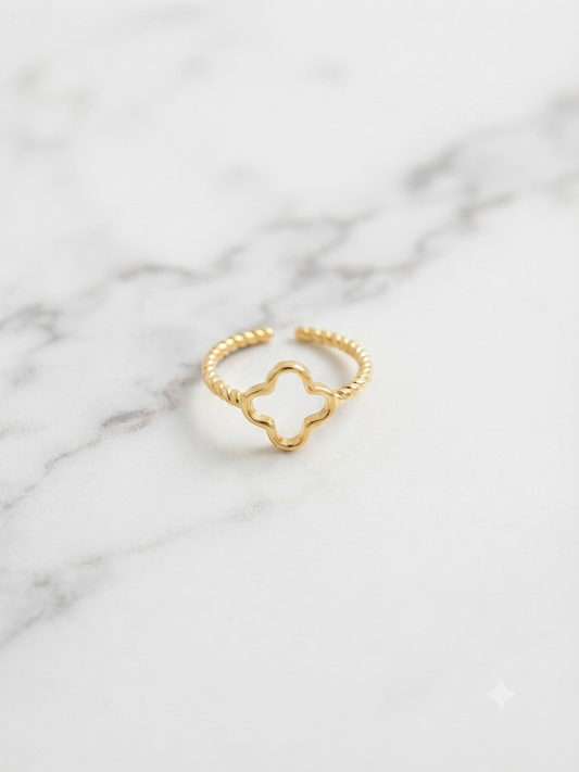 Bague Trèfle dorée ajourée posée sur marbre, gros plan sur le motif