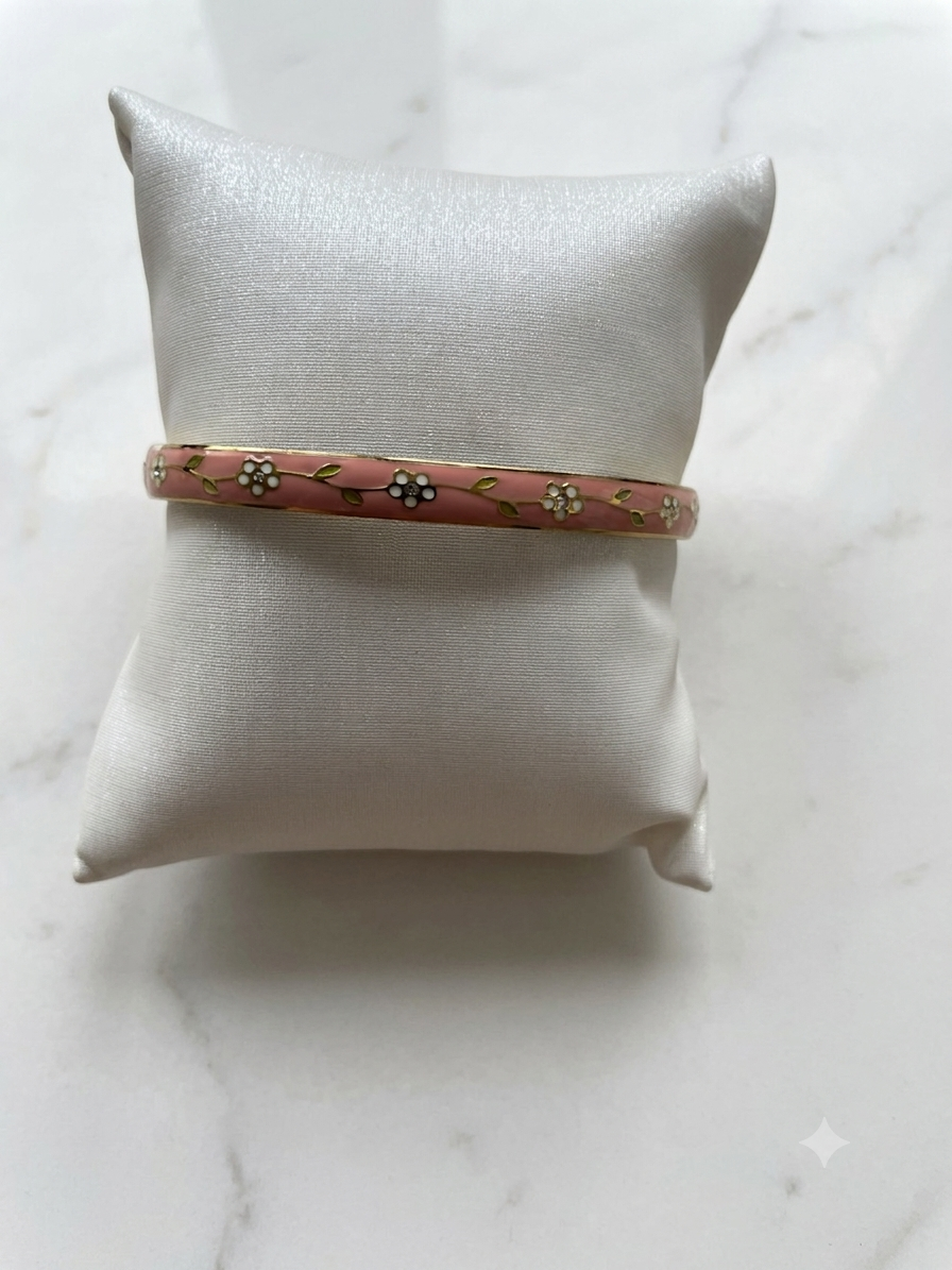 Jonc Aloha corail en acier inoxydable motif fleuri, posé sur fond marbre blanc