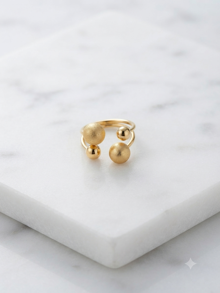 Bague Georgia aux perles dorées graduées, posée sur fond marbre blanc