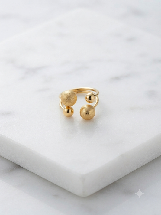 Bague Georgia aux perles dorées graduées, posée sur fond marbre blanc