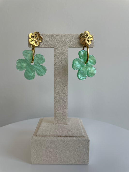 Boucles d'oreilles Sola avec pampille fleur en résine vert marbré et puce fleur dorée, posées sur présentoir - Maëlyne Beauty