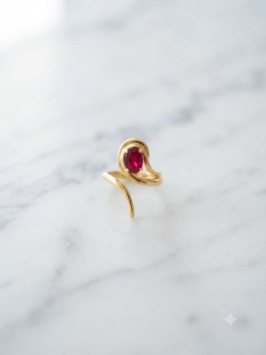 Bague Olivia torsadée à pierre rubis, posée sur fond marbre blanc