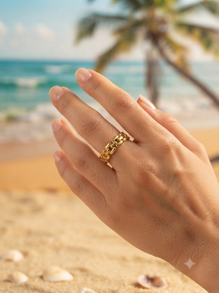 Bague Lucia dorée maillons entrelacés portée à la main, ambiance plage