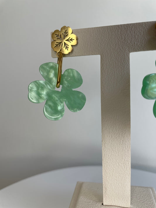 Gros plan sur la boucle d'oreille Sola, puce fleur dorée et fleur vert marbré